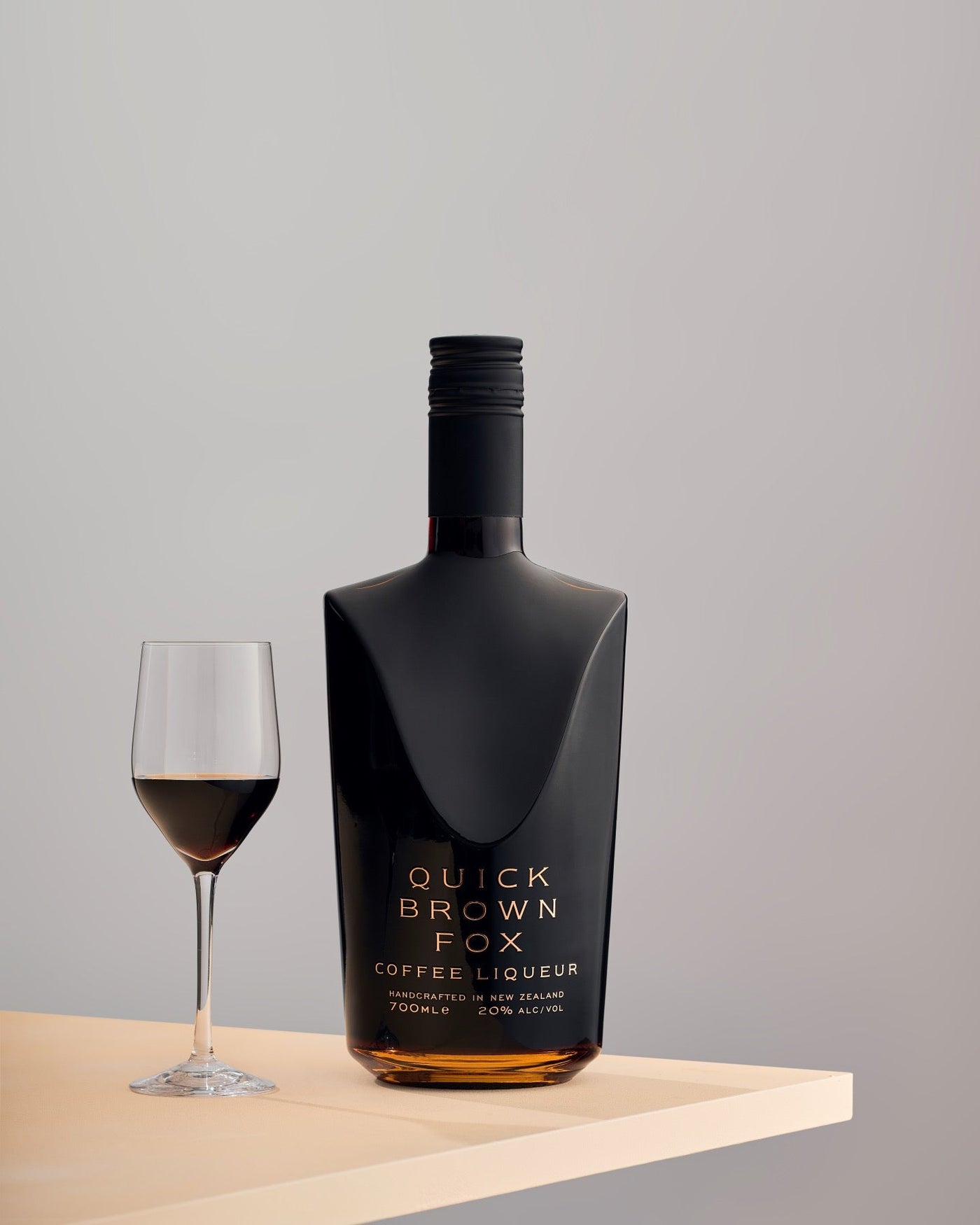 Quick Brown Fox Coffee Liqueur on a table edge with a glass