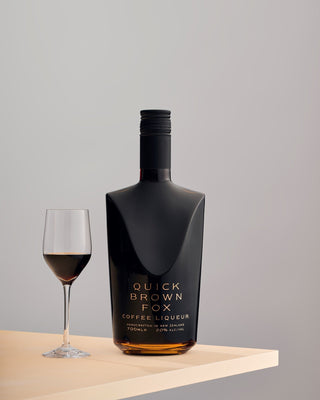 Quick Brown Fox Coffee Liqueur on a table edge with a glass